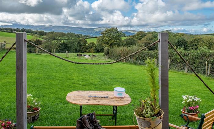 The hut looks out past the paddock, over the farm fields, and on to the Carneddau mountains beyond.  There are cows and trees and it is very green.